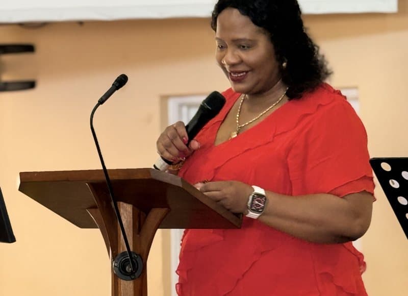 Pastor Catherine ministering at the lectern in a red dress